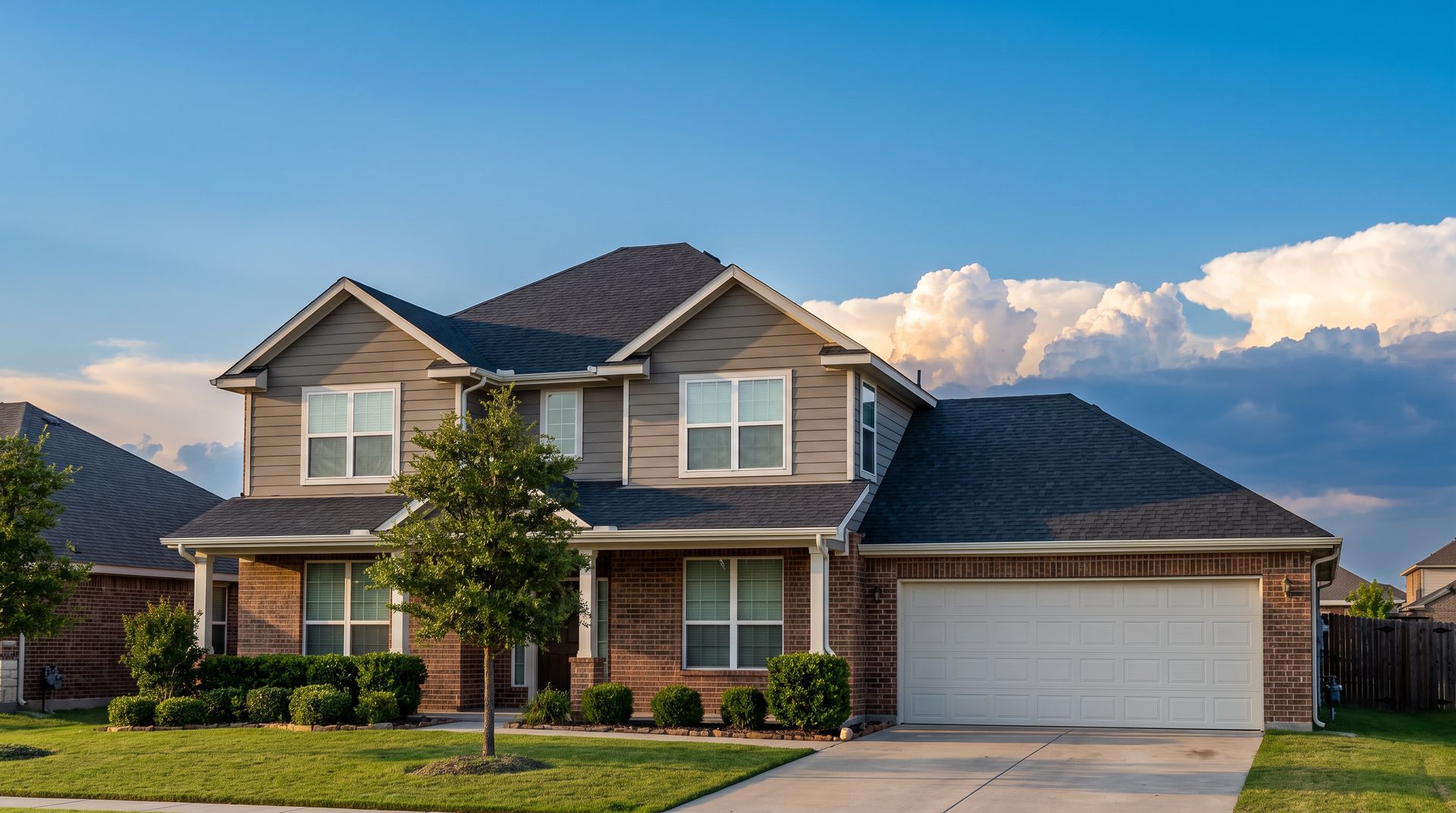 Example two-story home as it stands: a shingle roof and a wide garage door, with storm clouds building behind it.
